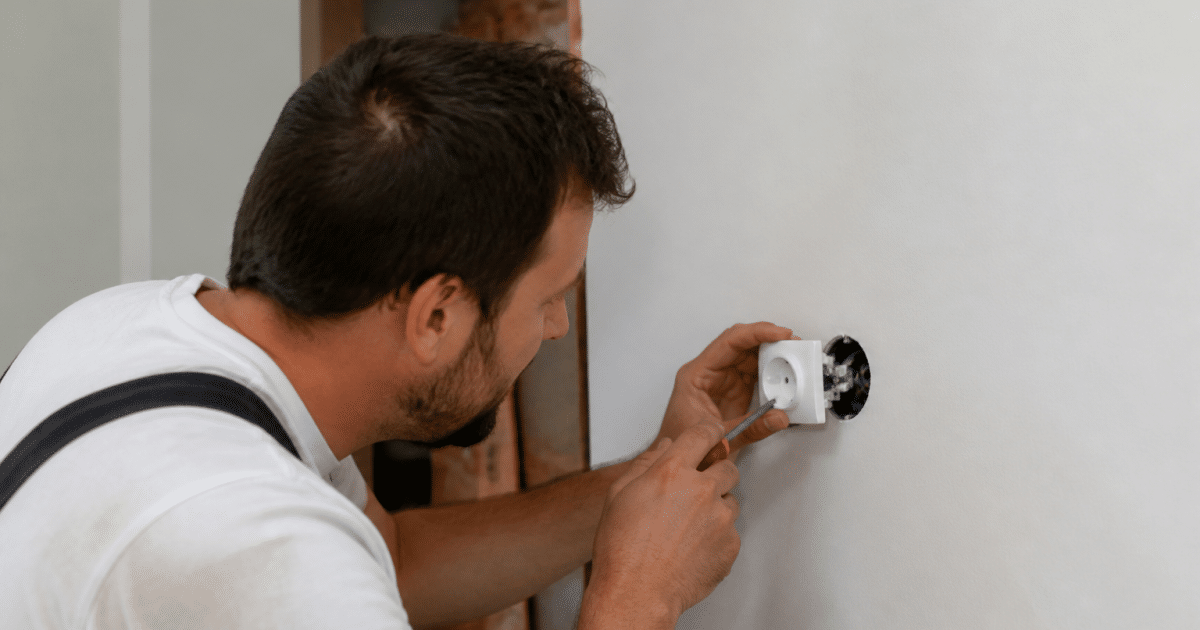 Electricien installand une prise murale blanche sur mur rénové