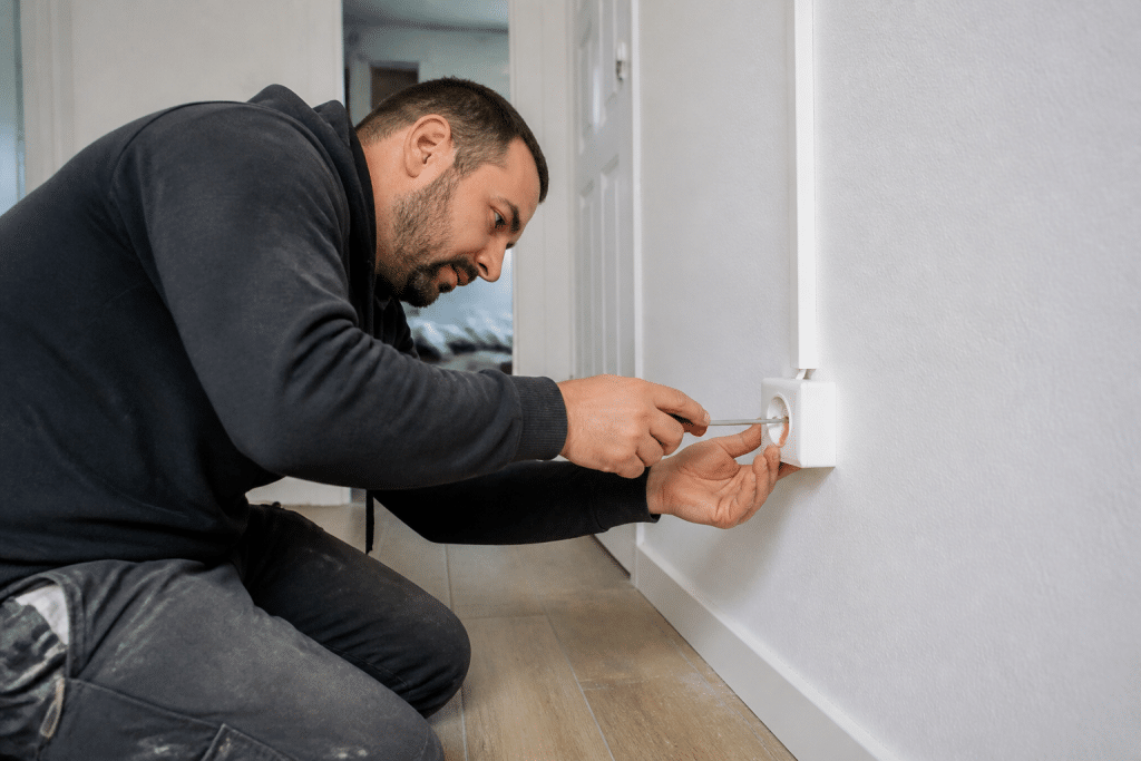 Electricien installant prise murale blanche en saillie