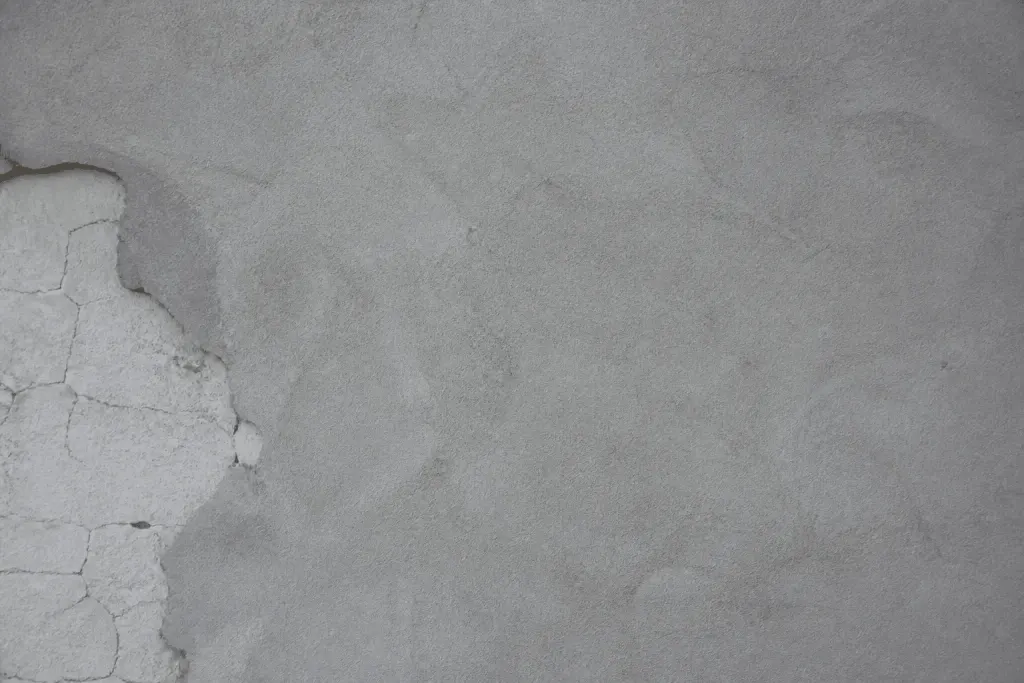 Mur blanc avec fissures recouvert d'enduit gris lisse