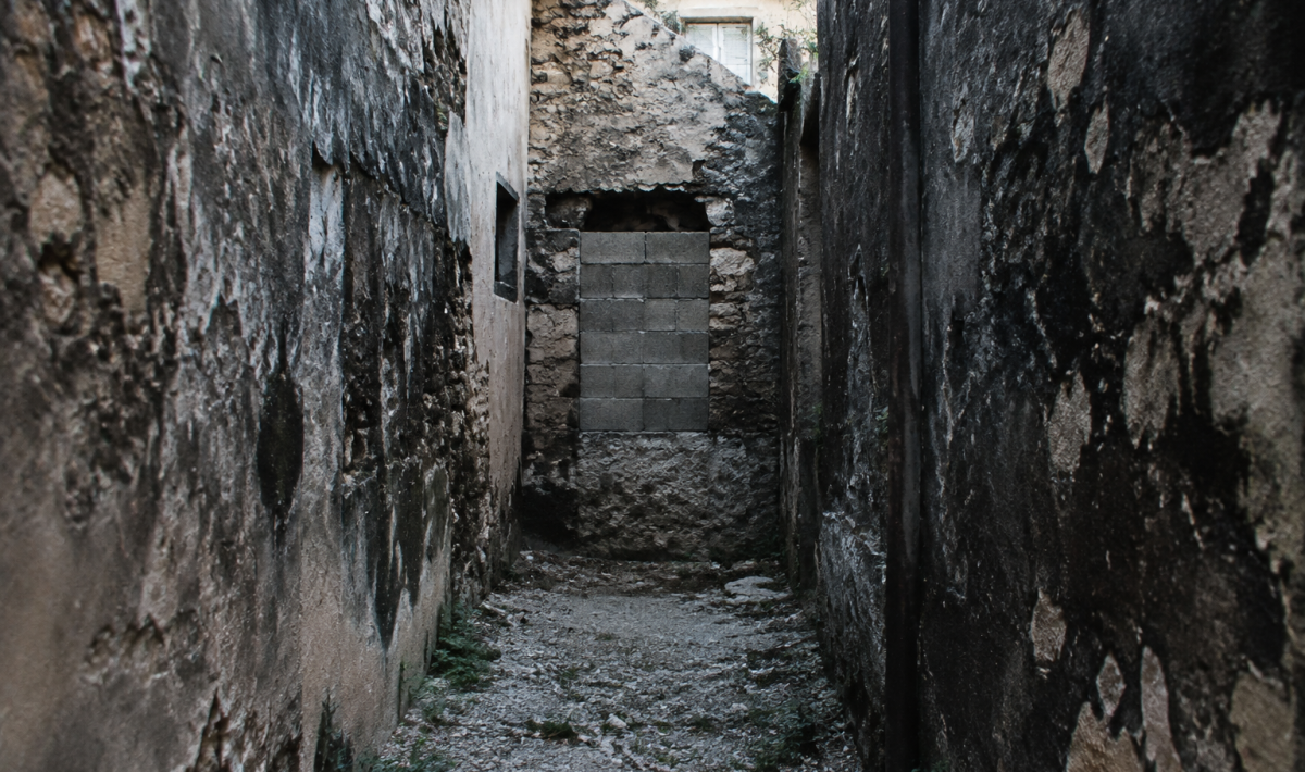 Ruelle delabree avec murs noircis et entree condamnee