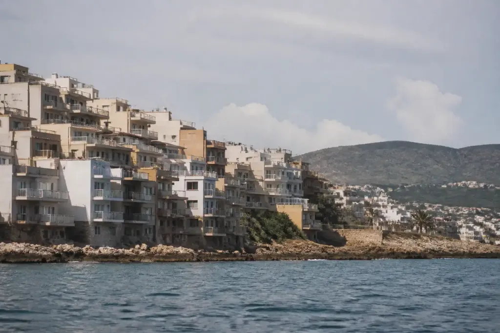 Immeubles compacts en front de mer, collines au loin