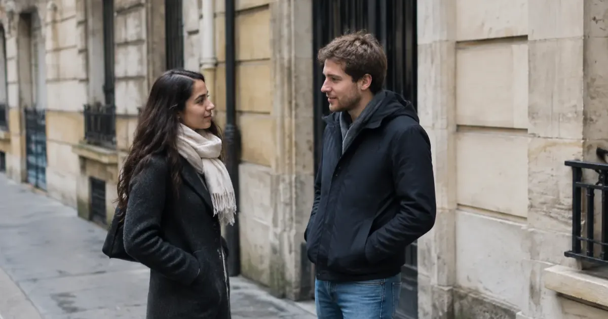Deux passants debout sur trottoir devant immeubles en pierre